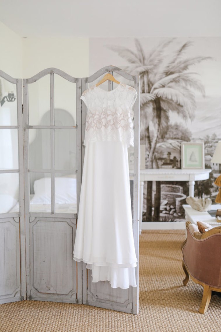 Robe de la mariée suspendue dans une chambre lumineuse du Château de Séréville, les préparatifs