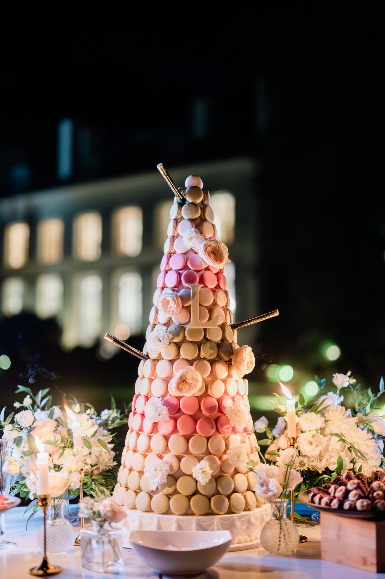 Pièce montée de macarons devant le Château de Séréville illuminé, la nuit