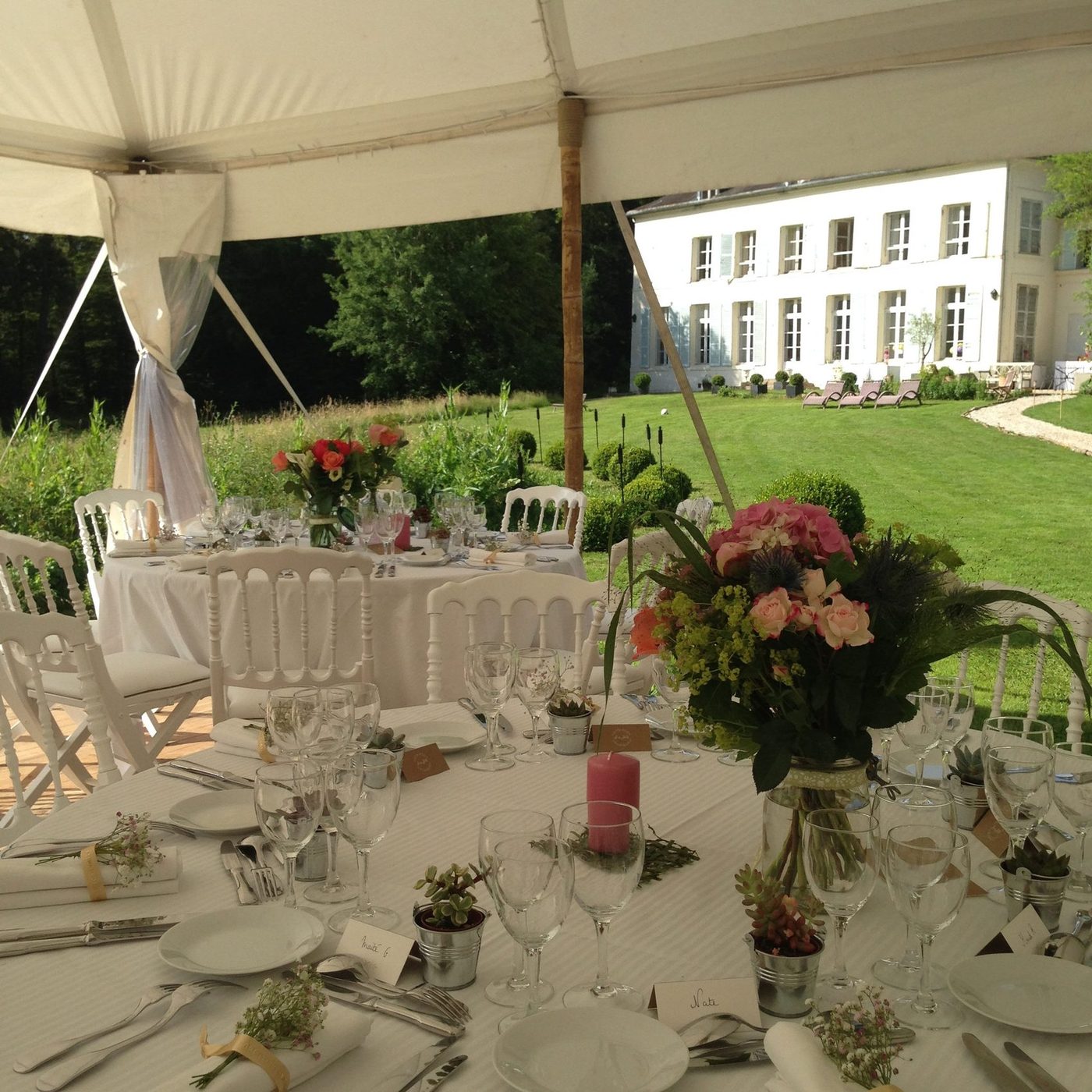 Tables dressées sous le chapiteau, ouvertes sur la pelouse et la façade du château